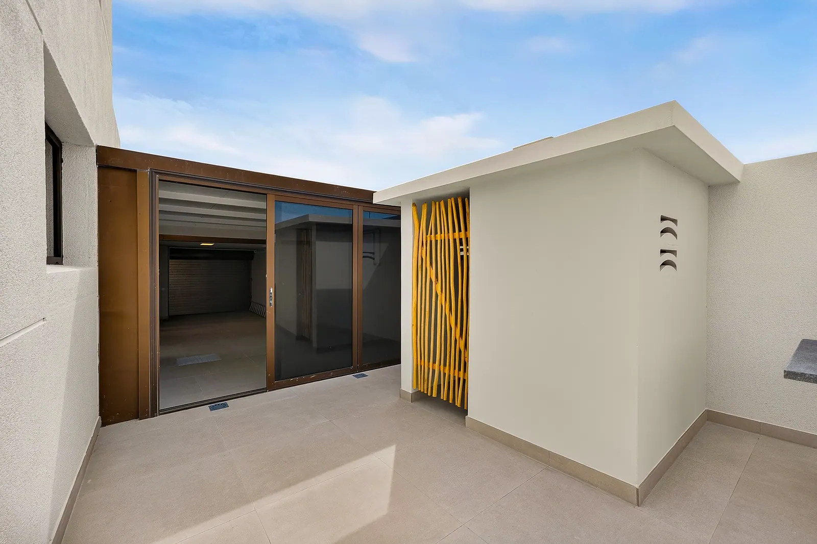 Fachada interior con celosía de madera y acceso al salón