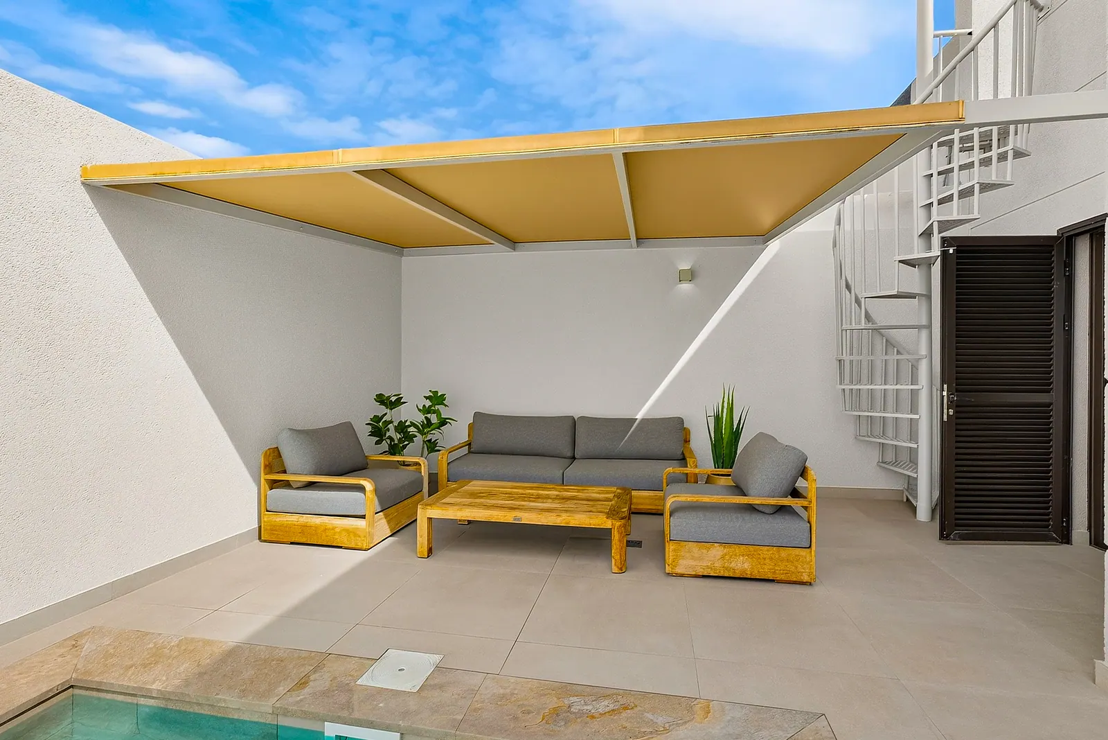 Zona de estar cubierta con toldo junto a la piscina