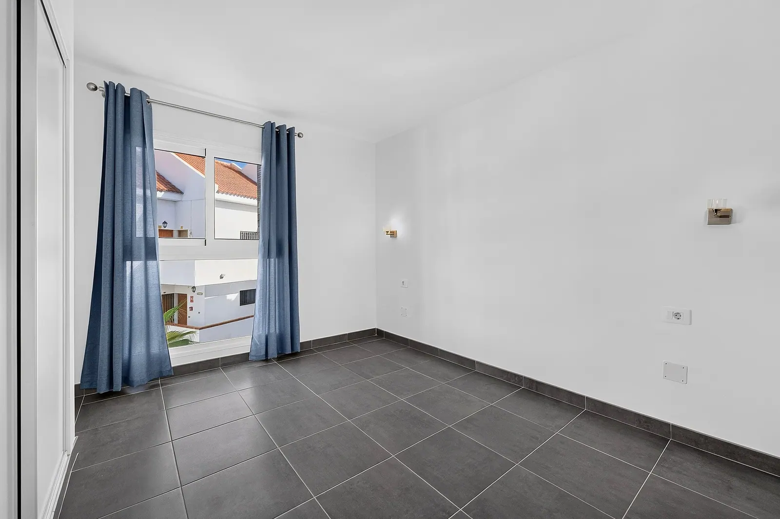 Dormitorio con ventana y cortinas azules