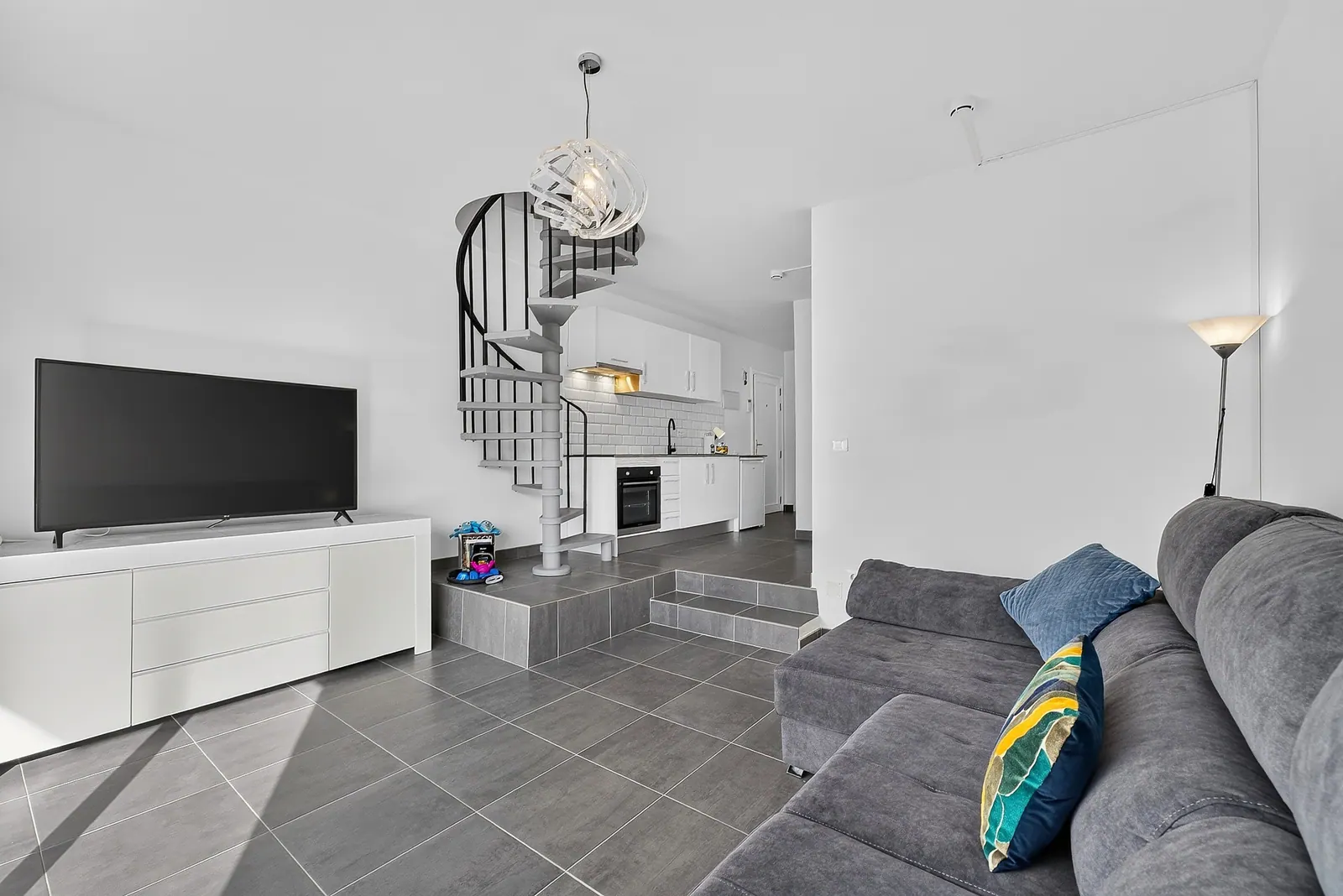 Salón con sofá gris y televisión
