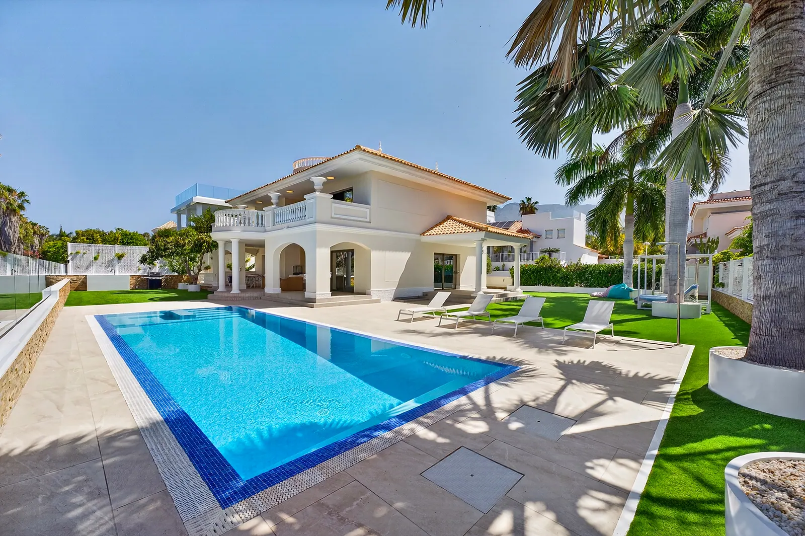 Piscina privada con solárium y palmeras