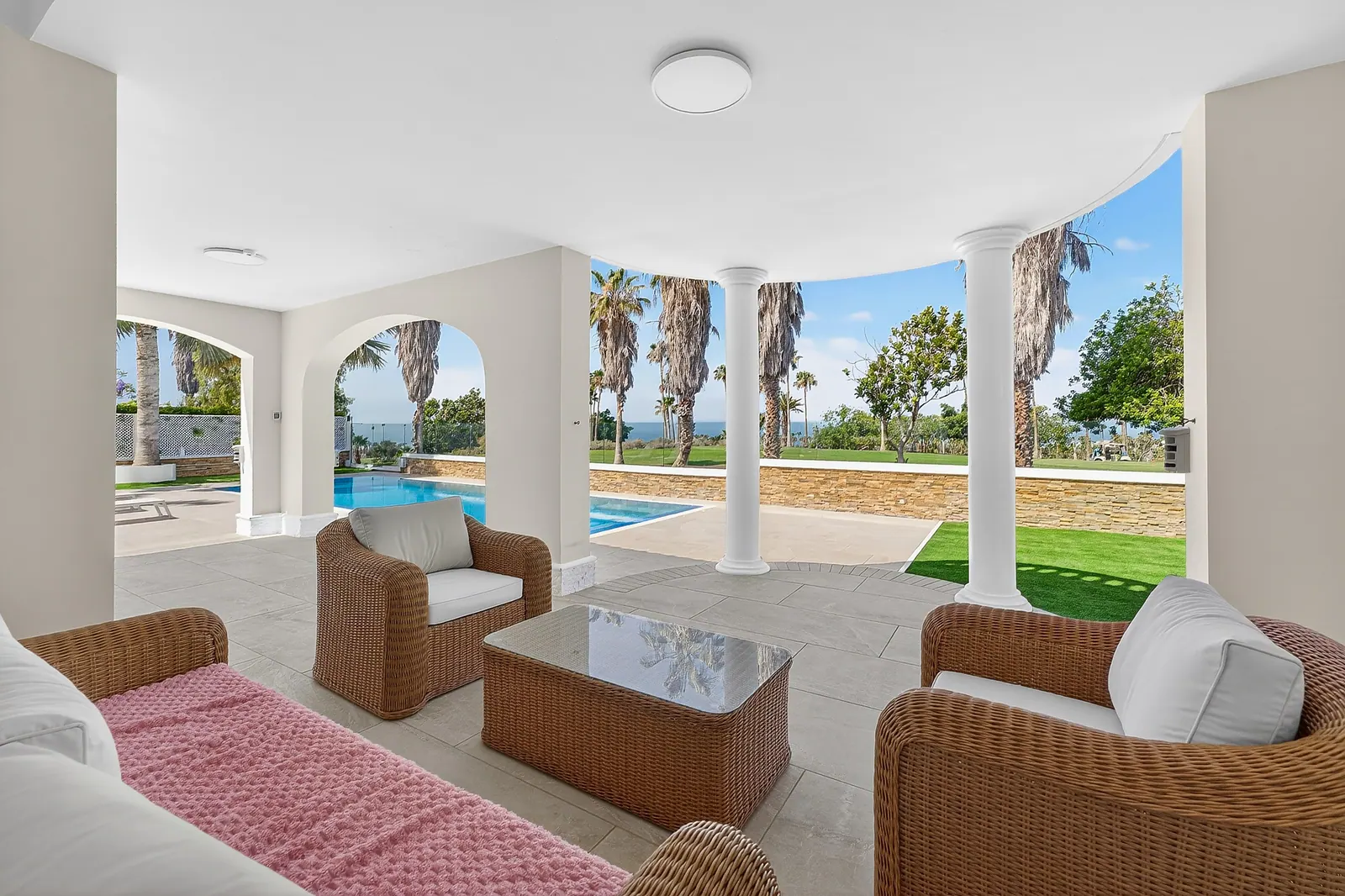 Porche con sofás de ratán y vistas a la piscina